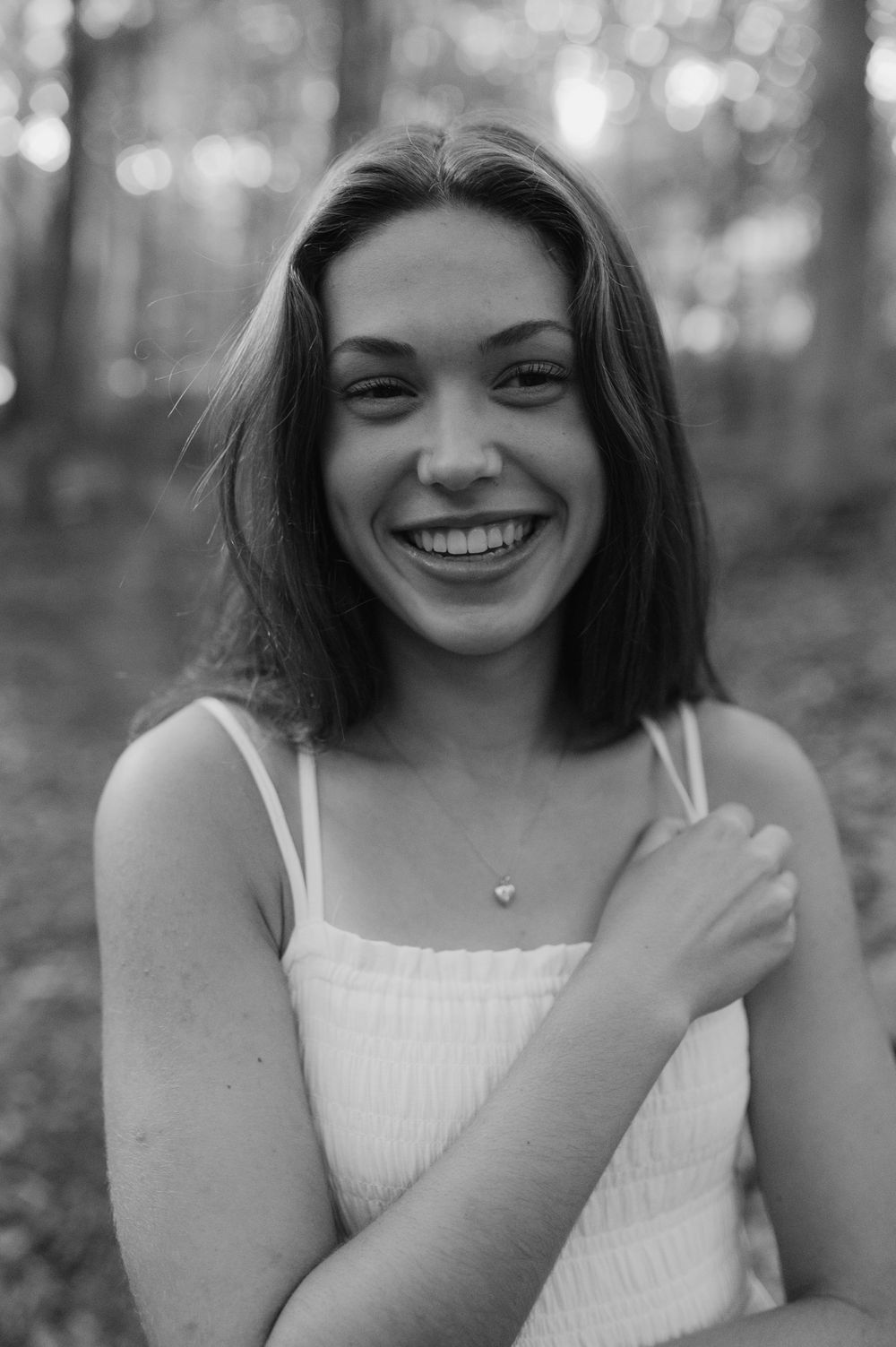 A candid black and white portrait captures a joyful expression in a forest setting.