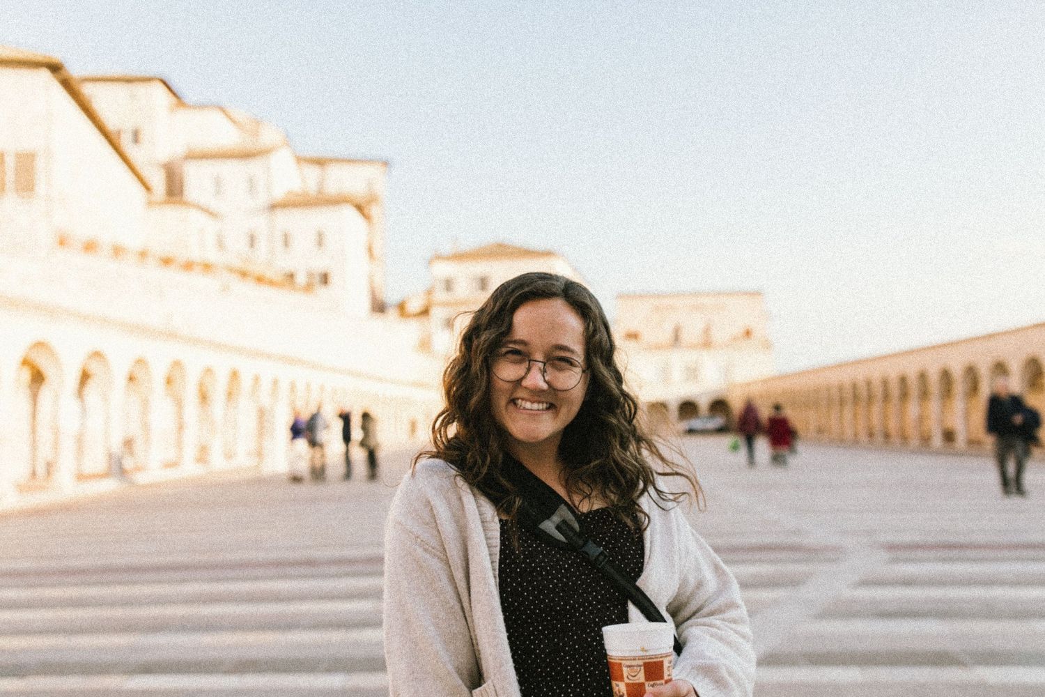 A woman poses at a historic site with classical architecture and columns in the background.