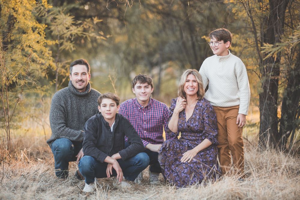 Natural outdoor family portrait session in a golden autumn field setting.