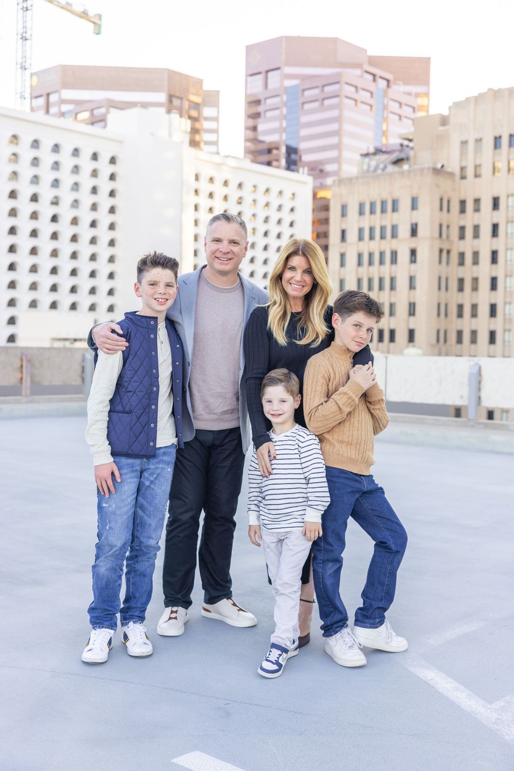 Family members smile and pose together on rooftop with urban skyline backdrop.