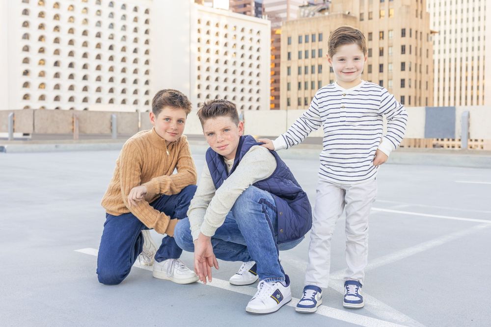 Family group poses playfully on urban rooftop with city buildings in background.