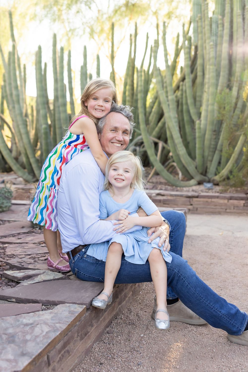 Family poses together among tall desert cacti during outdoor portrait session.