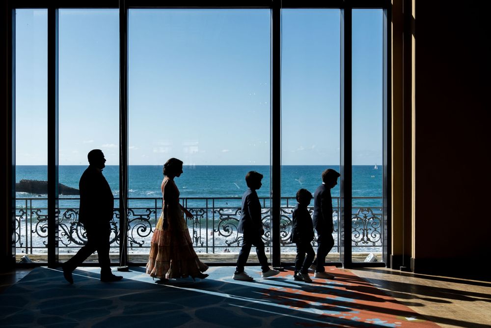 Famille marchant en silhouette face à de grandes baies vitrées donnant sur la mer, lumière naturelle et cadre élégant. Casino de Biarritz.