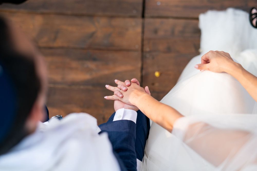 Gros plan sur la main du marié, le Hatan, saisie délicatement par sa femme , la Kala, scène douce et intime lors d'un mariage juif