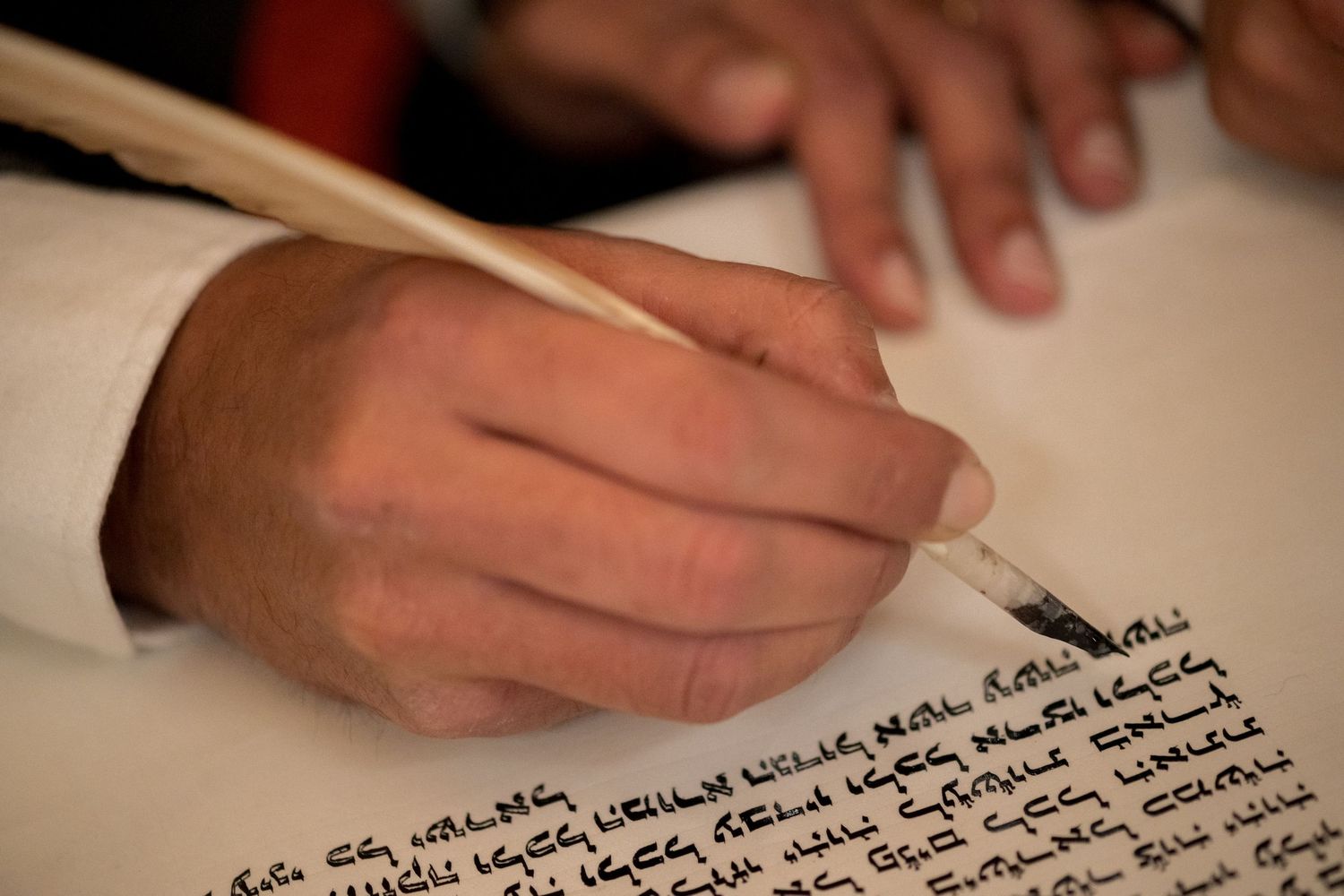 Gros plan sur la finalisation d'un Sefer Torah dans la synagogue des Tournelles, geste traditionnel capturé avec finesse.