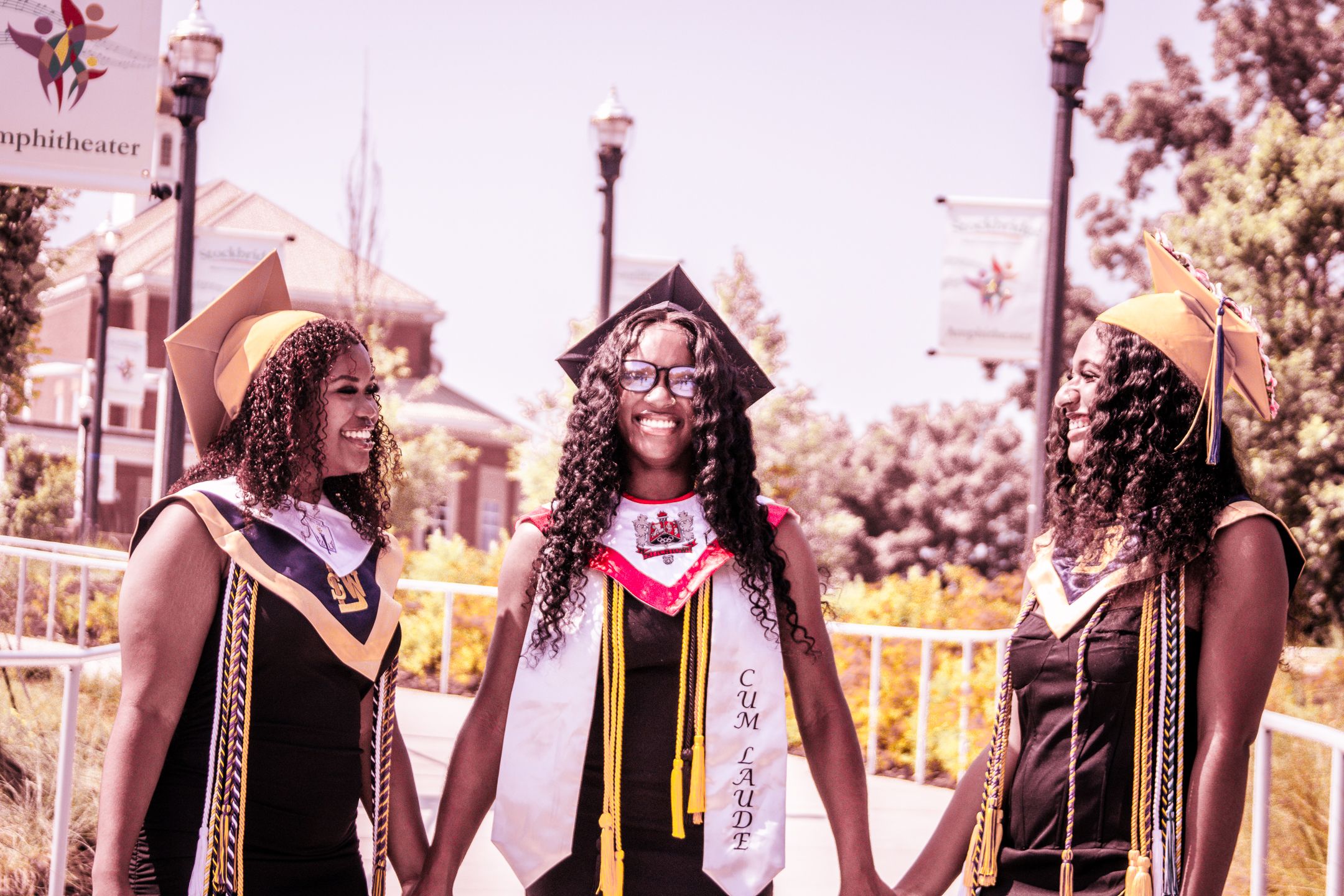 Vintage-style photo of graduates in academic regalia standing by decorative lamp posts.