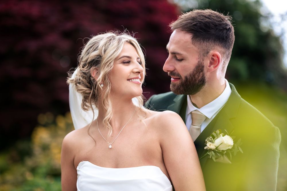 Romantic wedding couple embracing in a lush garden setting during golden hour.
