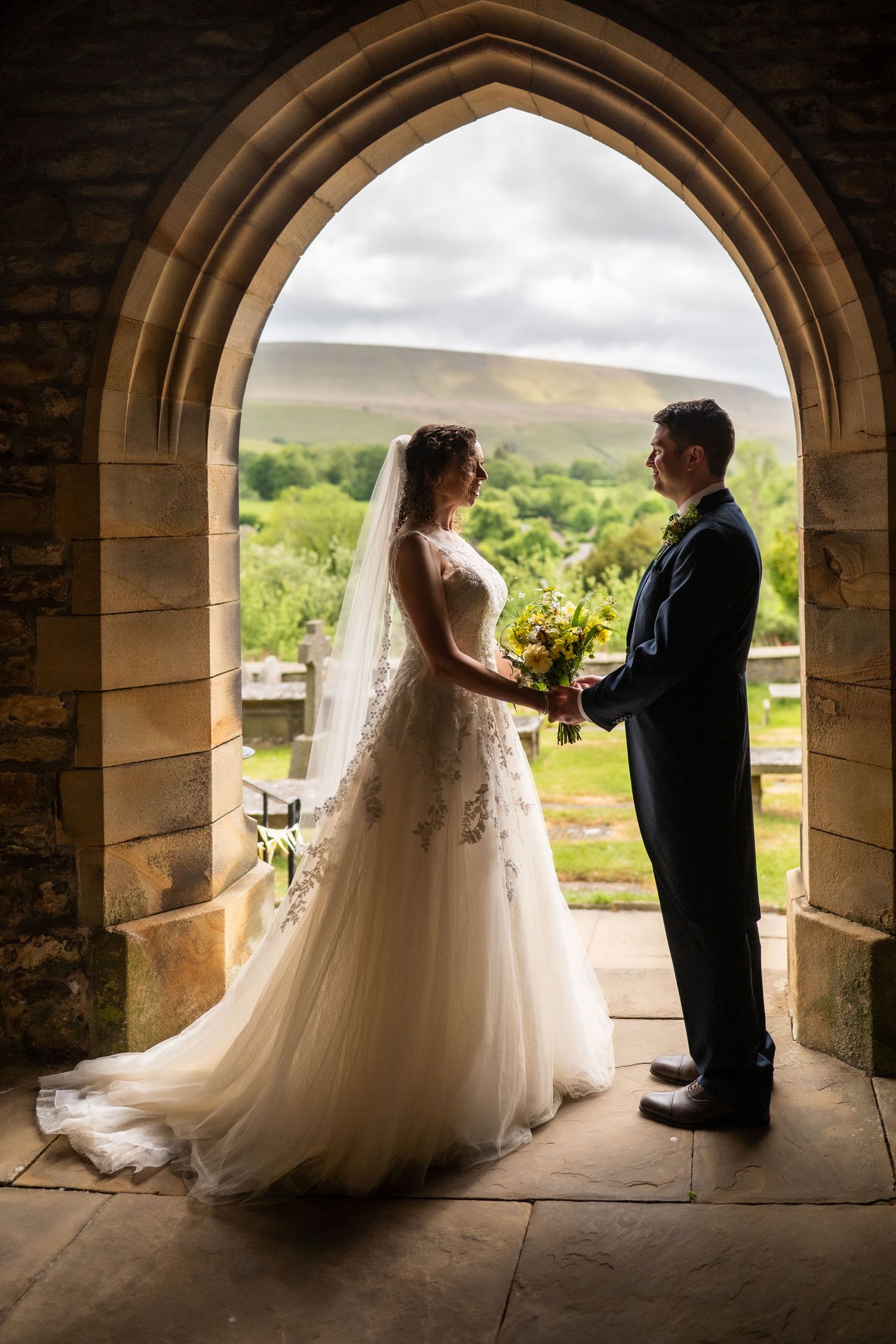 A romantic wedding photoshoot sequence showing a couple in silhouette under a stone archway at a countryside venue.