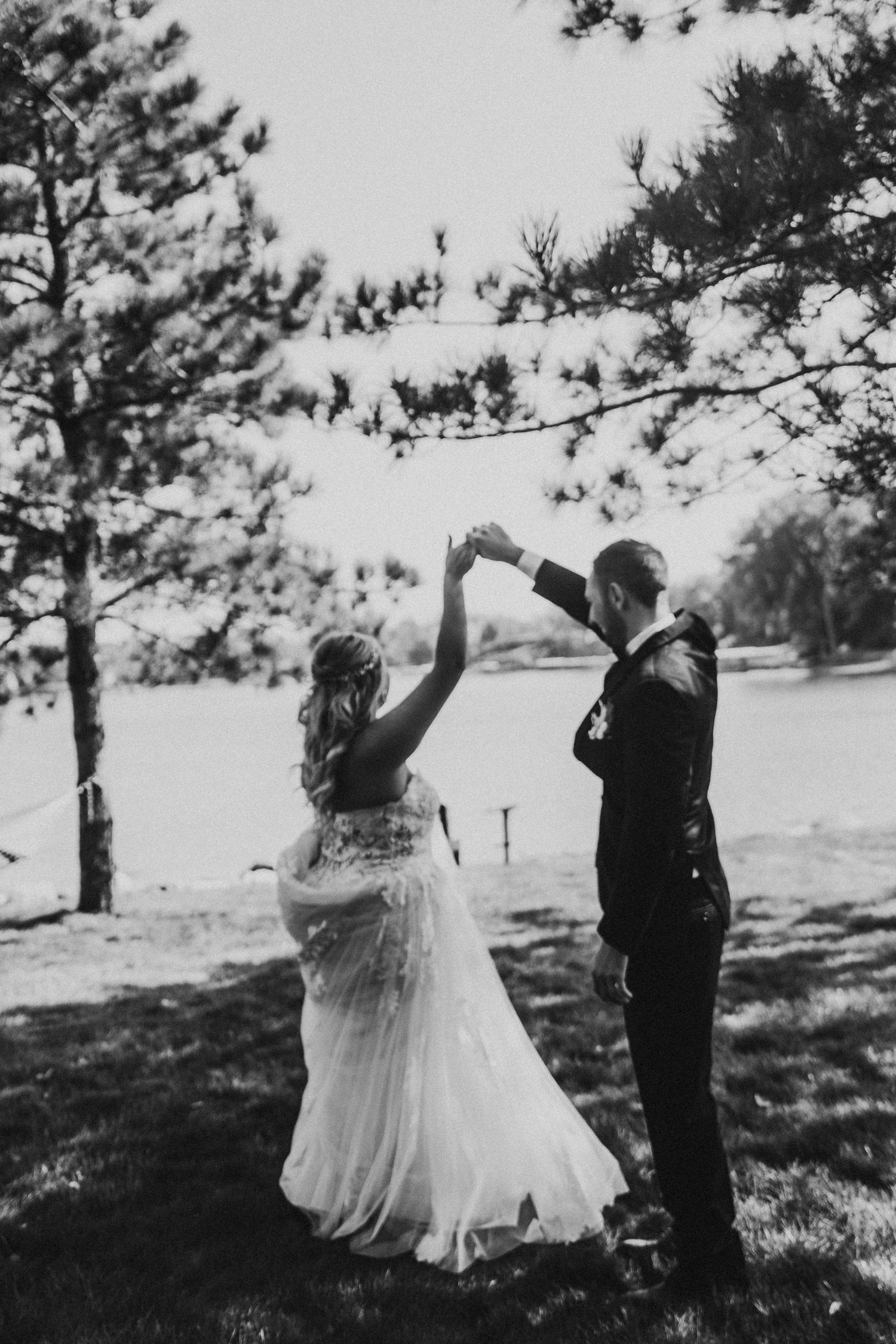 A couple dancing together under pine trees in a romantic black and white photo.