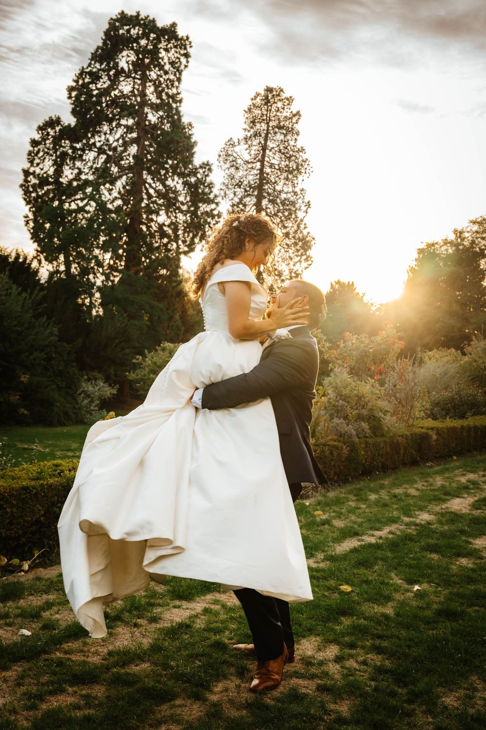 Sunset portraits at Berkeley Castle Gloucestershire Wedding groom lifting bride