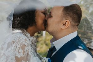 A romantic close-up of a bride and groom sharing tender kisses in a garden setting.