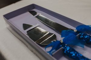 A silver iPhone is being unboxed from its retail packaging with a blue ribbon accent.