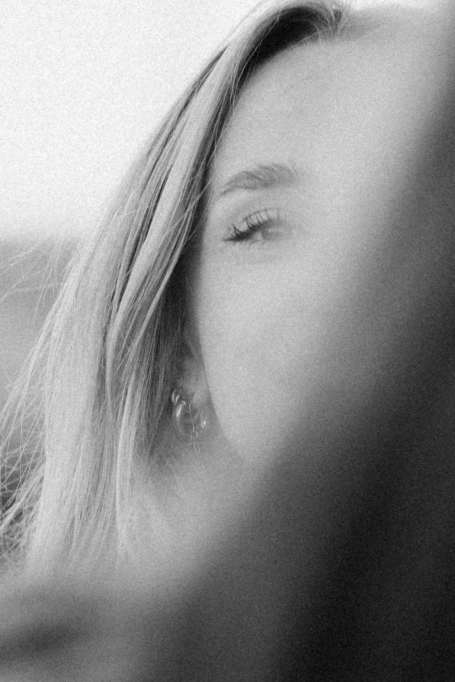 Close-up black and white portrait of a young woman with long blonde hair and closed eyes.