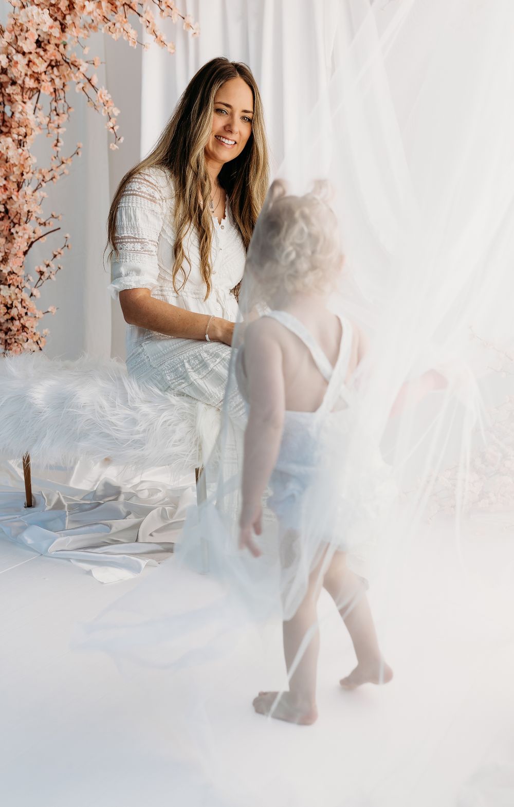 A dreamy portrait session featuring ethereal white clothing and soft pink floral decorations against a light backdrop.
Rashinphotography-DMV