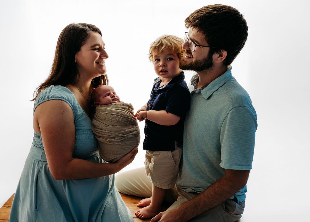 Family embraces and shares joyful moments together during outdoor photo session at sunset.