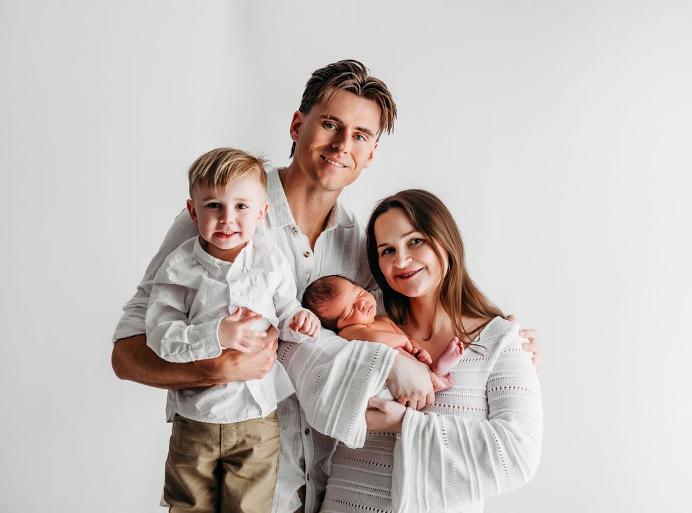 A family in coordinated white and gray outfits poses together against a light background in a series of photos.