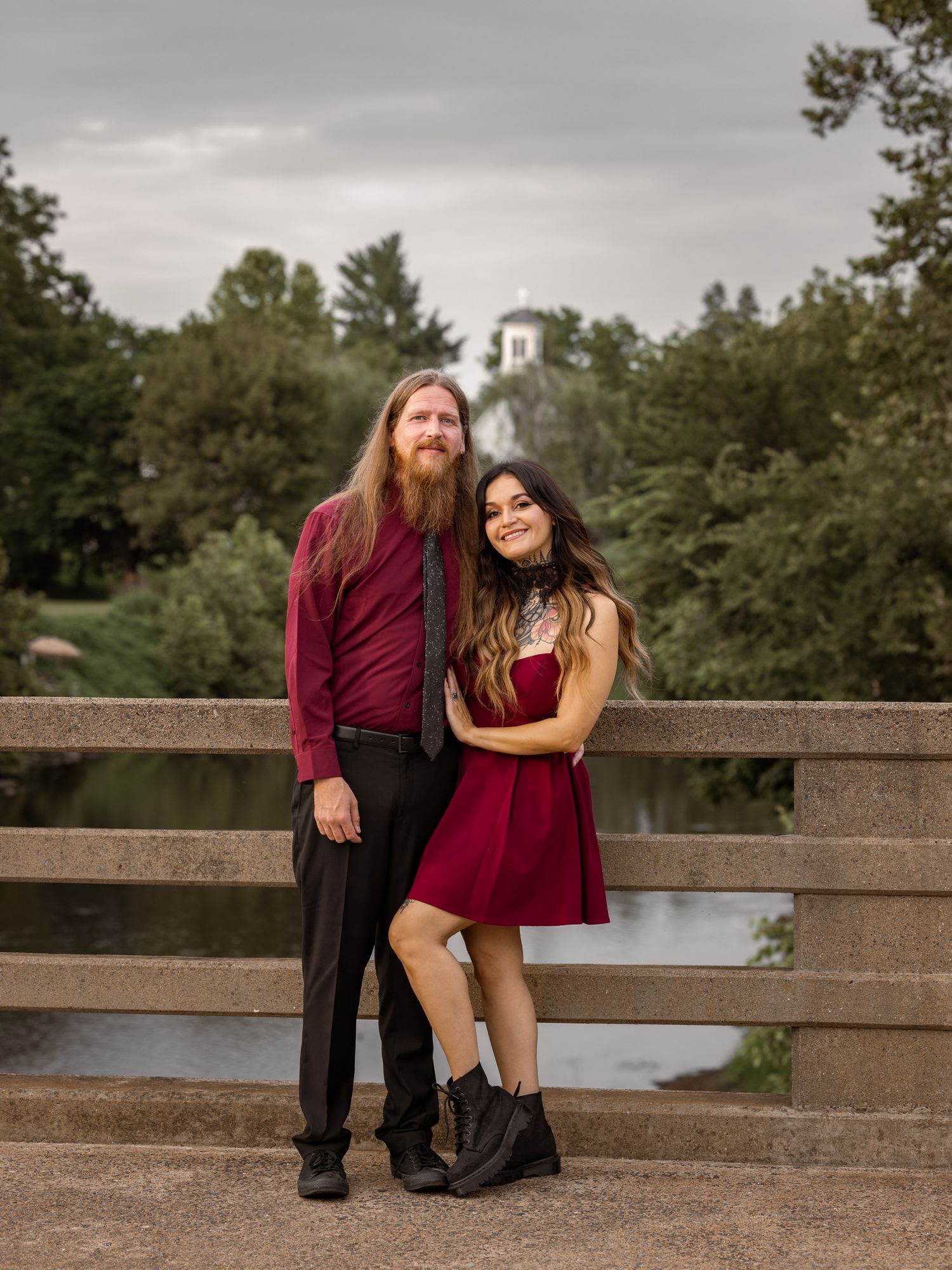 Couple after their engagement posing for a portrait on a bridge.