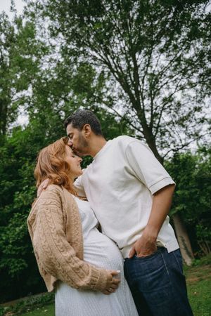 Intimate couple's photoshoot in casual attire against a natural outdoor backdrop.