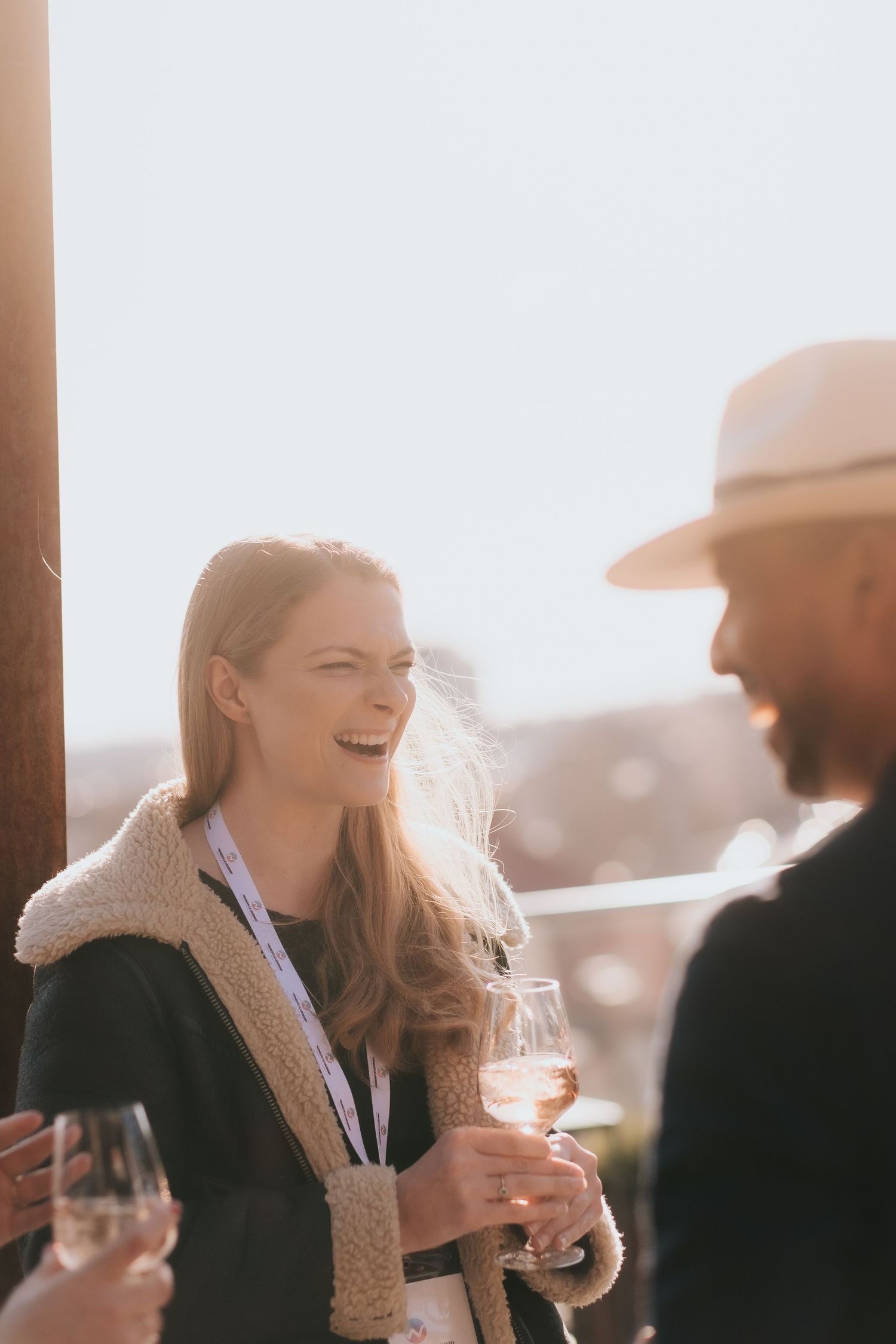 a girl laughing on a terrace of The Winery Hotel in Solna holding a glass of wine while being captured by event photographer in Stockholm