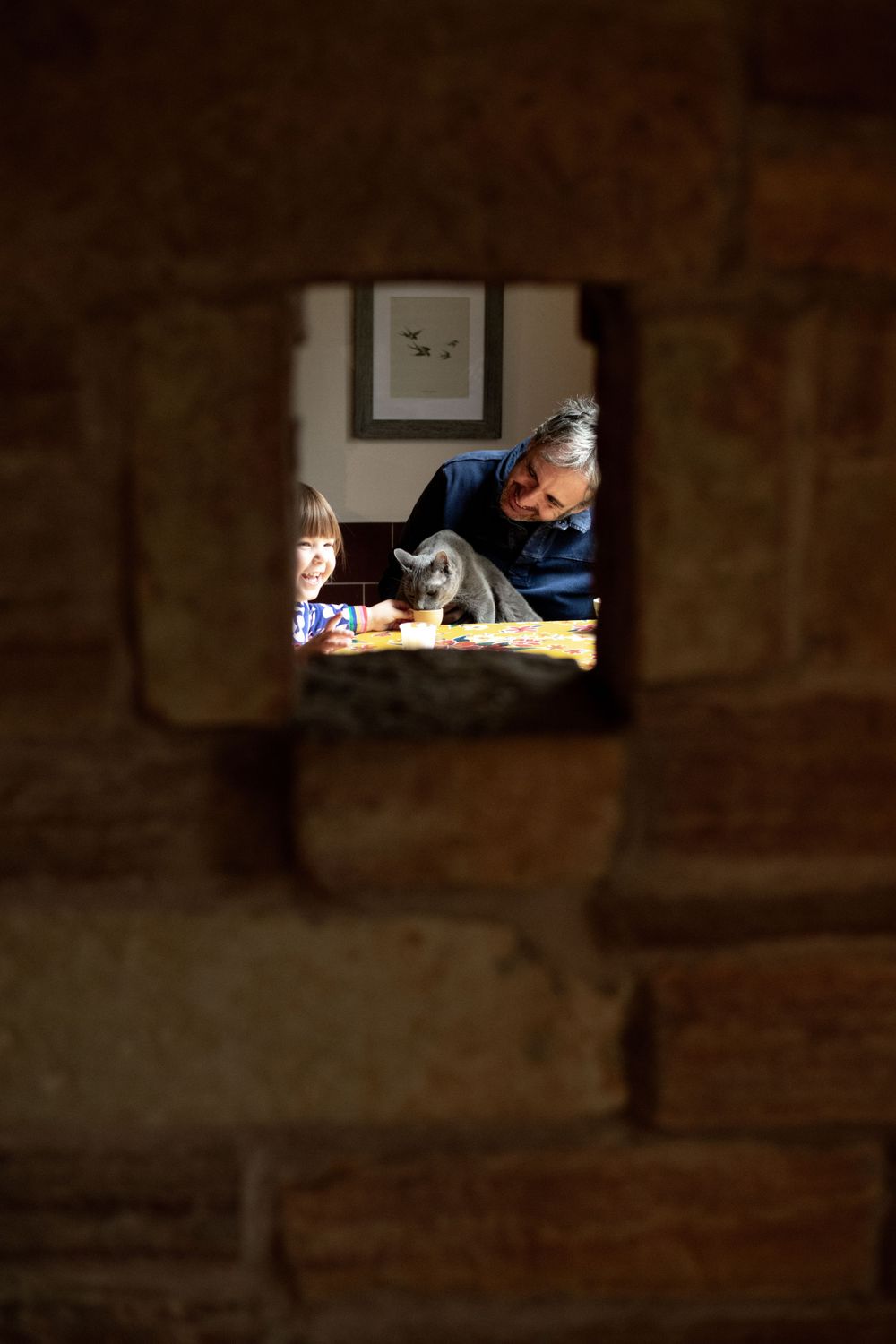 View through stone window opening of dimly lit indoor scene.