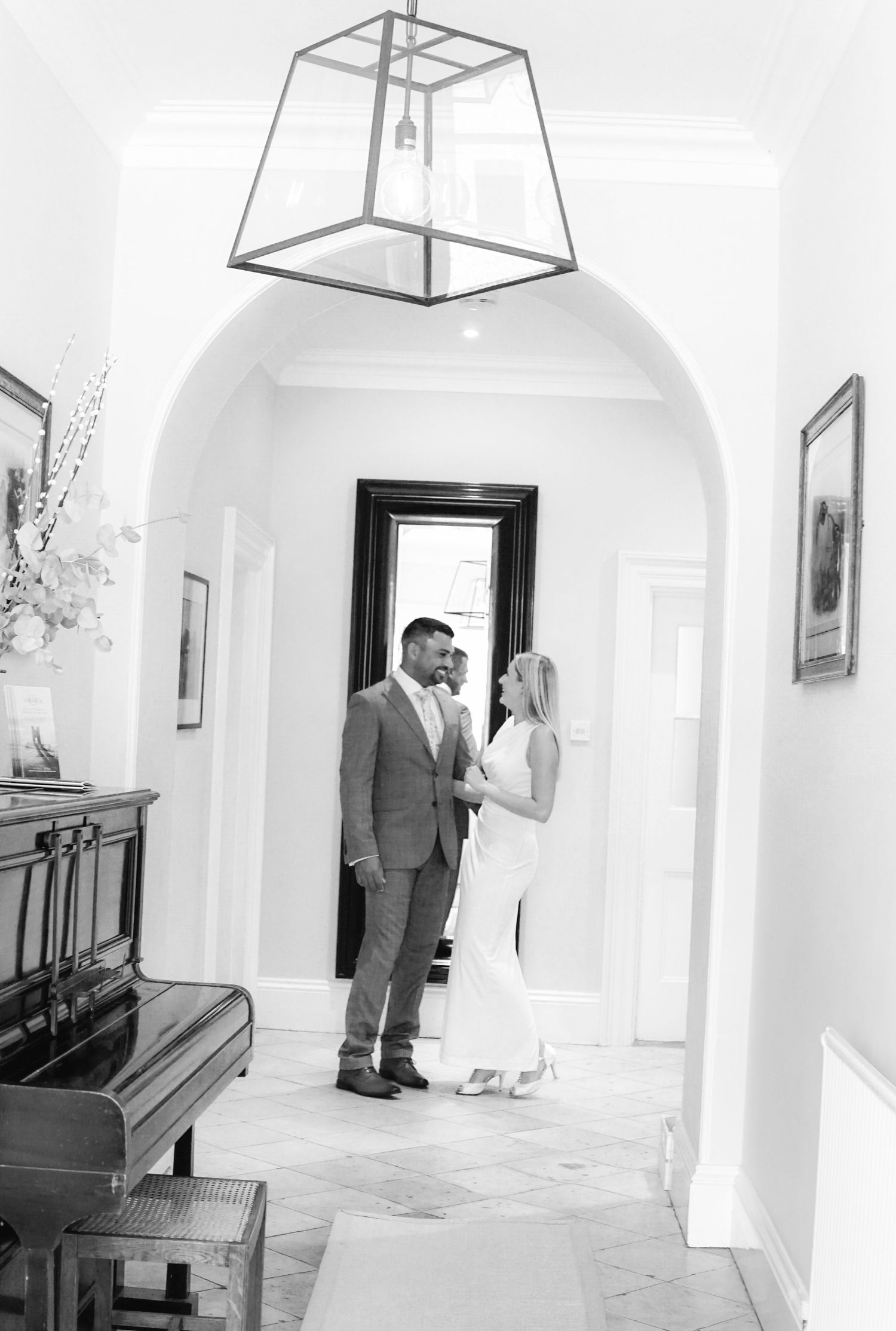 Timeless black and white image, couple standing side by side in sophisticated hallway setting.