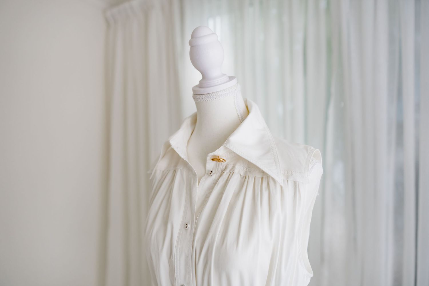 White vintage-style dress with high collar displayed on a mannequin against light background.