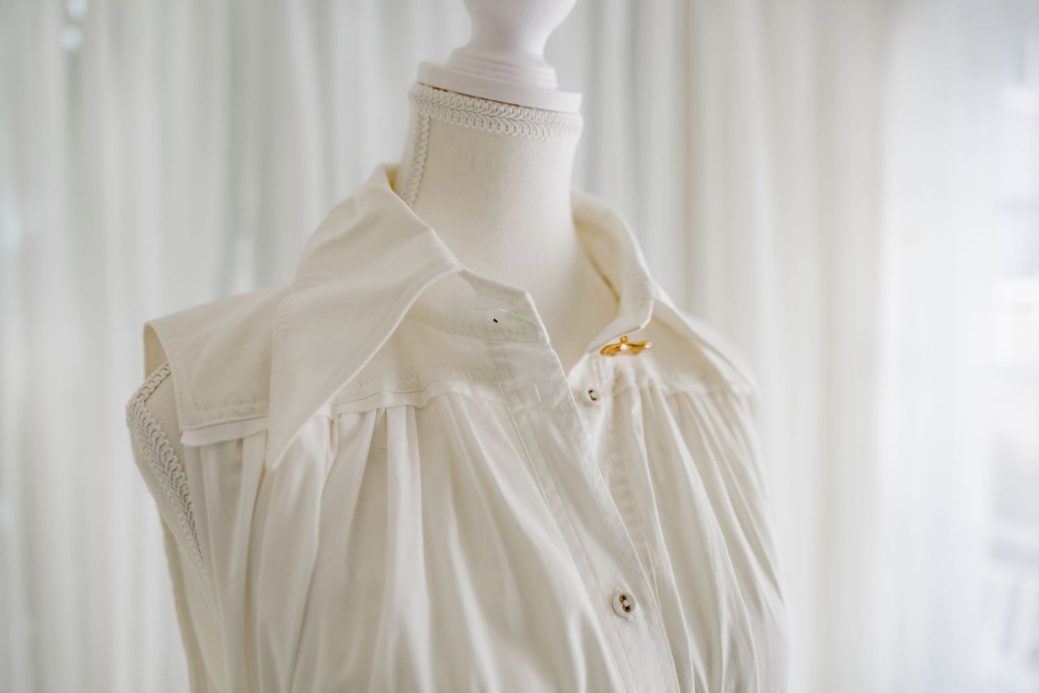 Close-up of white dress collar with pleated details on mannequin.