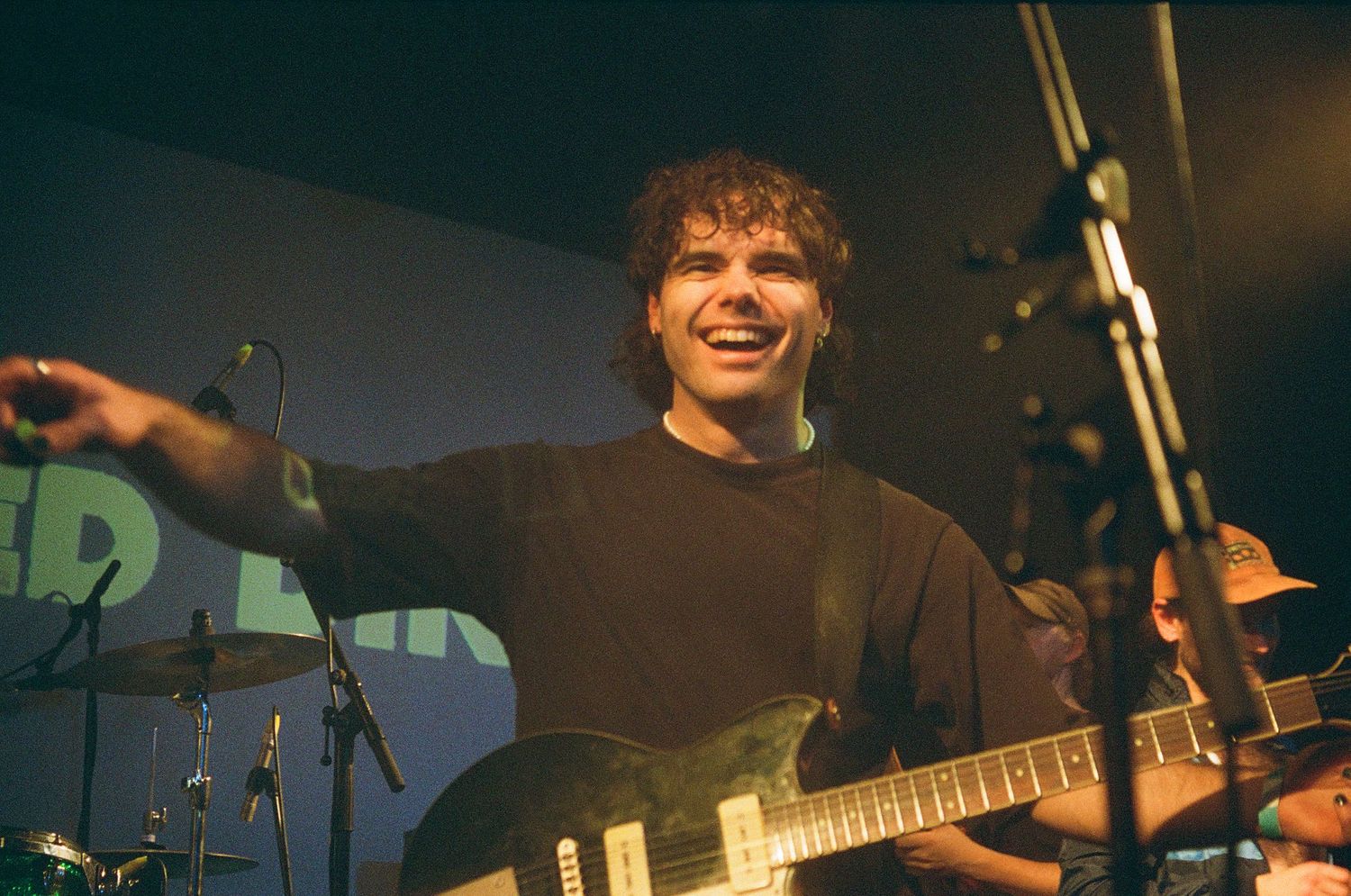 Musician performing on stage with electric guitar under concert lighting.