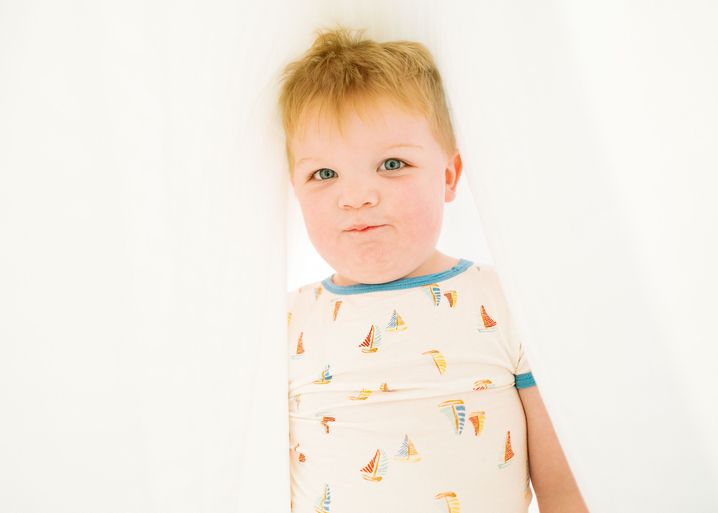 A baby wearing a white onesie with colorful fox prints sits against a bright white background.