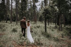 A romantic forest scene on a misty day with two figures walking among tall evergreen trees.