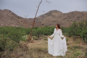 Elegant white dress contrasts with the earthy tones of a desert mountain backdrop.