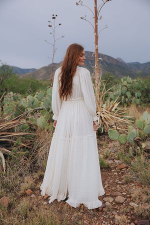 White dress movement captured in desert setting with mountains and cacti in background.