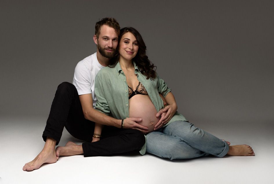 shooting photo grossesse couple allonges par terre a regarder l objectif du photographe pendant la prise de vue