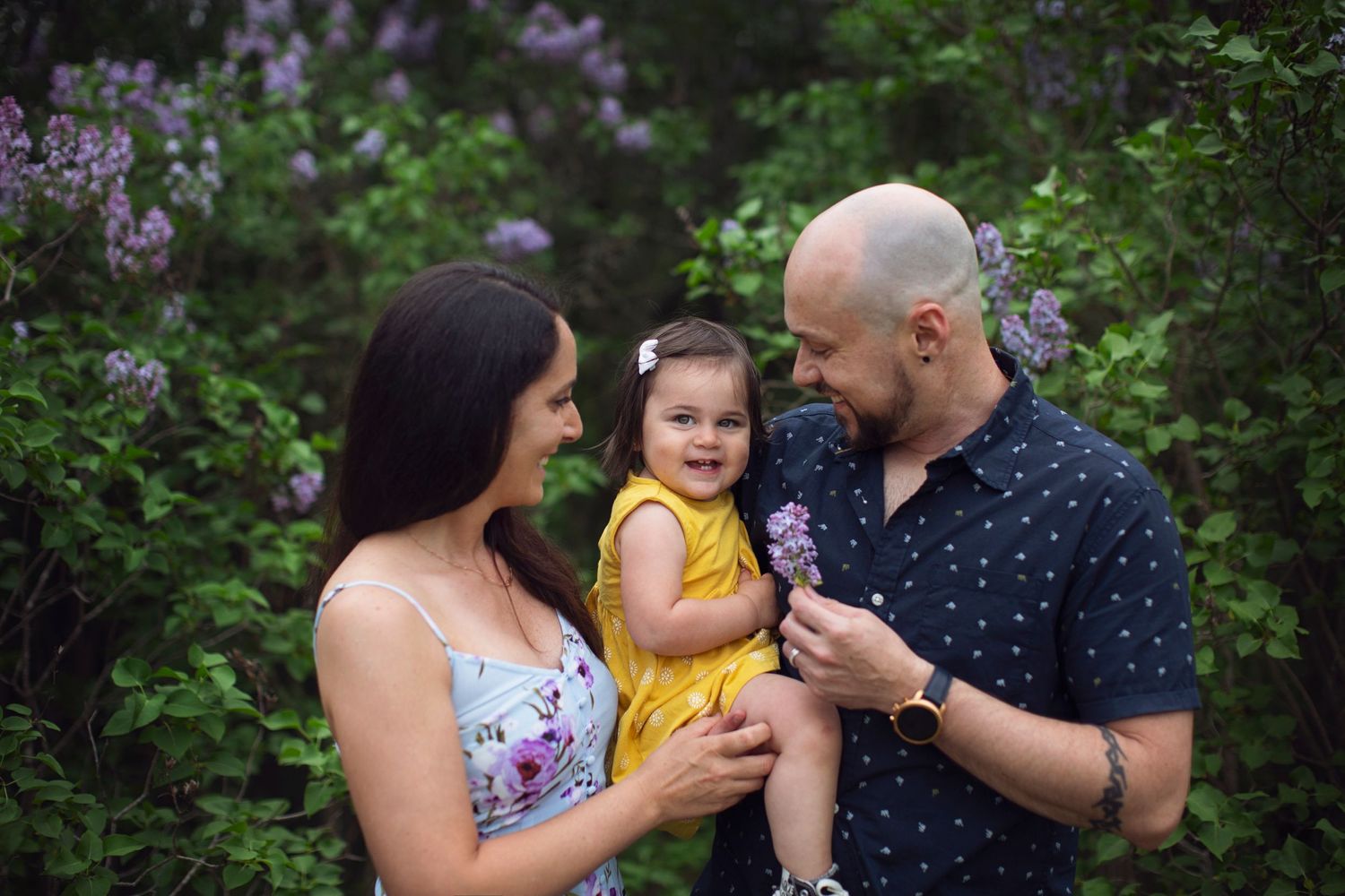 A tender moment shared in a blooming lilac garden on a warm spring day.
