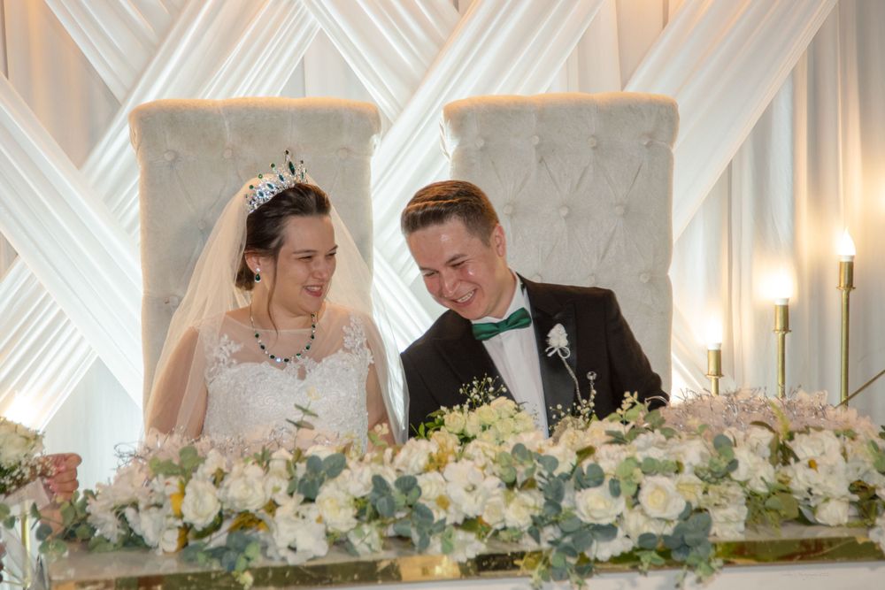 Newlyweds sitting at decorated wedding table with elegant floral arrangements.