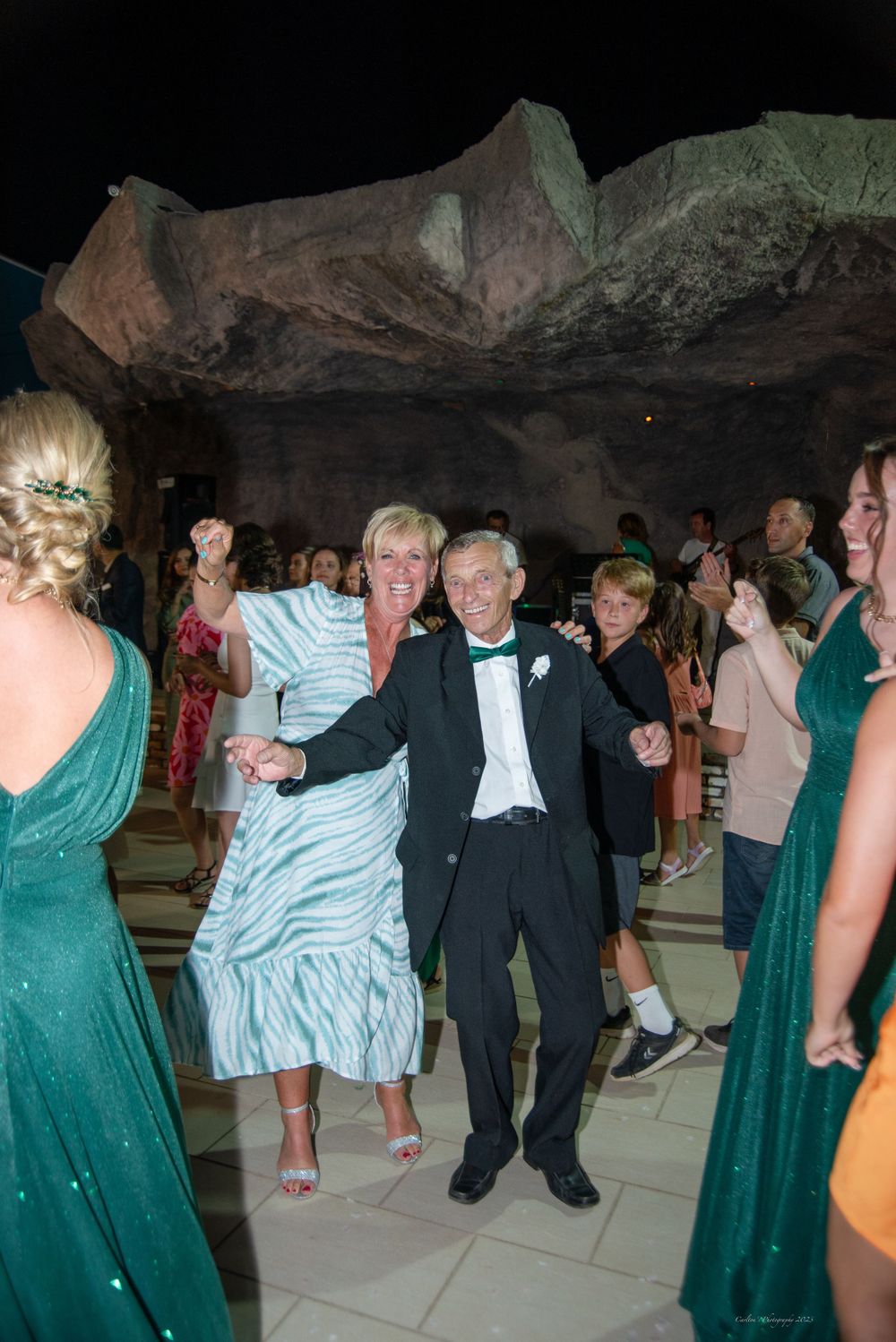 Wedding guests dancing and celebrating in venue with unique rock wall backdrop.