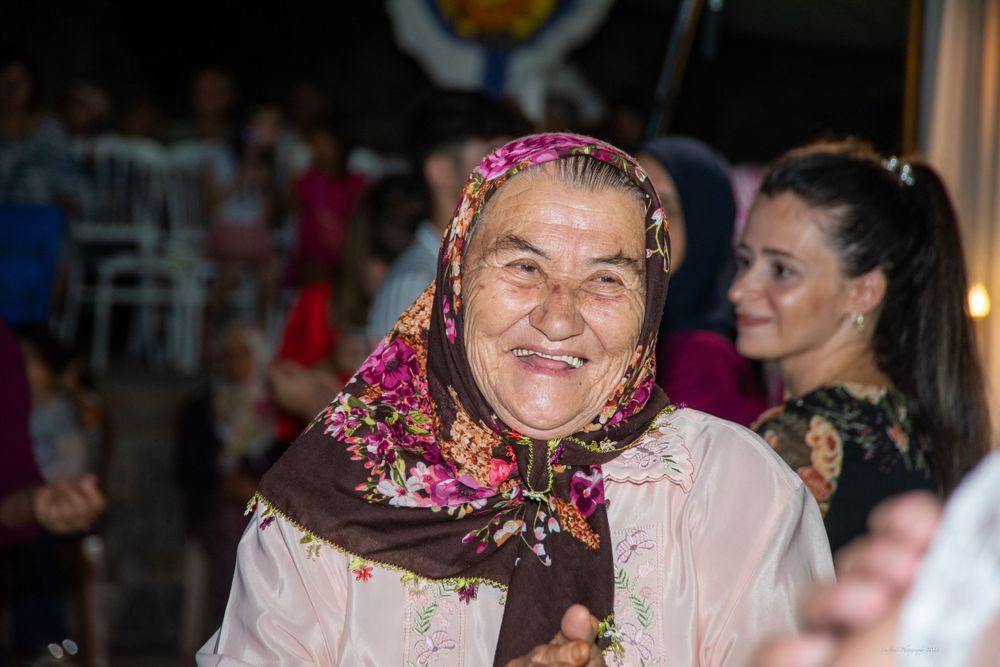 Wedding guest wearing traditional headscarf with colorful floral decorations.