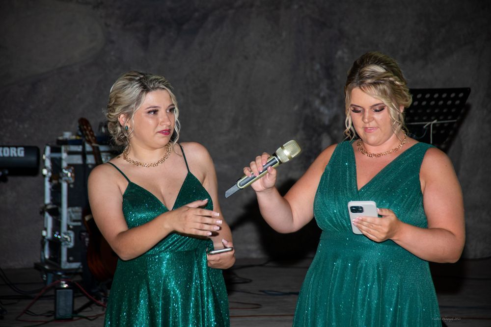 Bridesmaids in matching emerald green dresses performing during wedding reception.