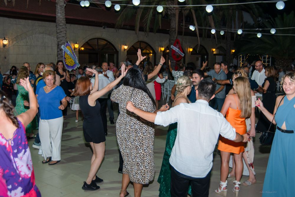 Lively dance floor filled with wedding guests beneath outdoor string lights.