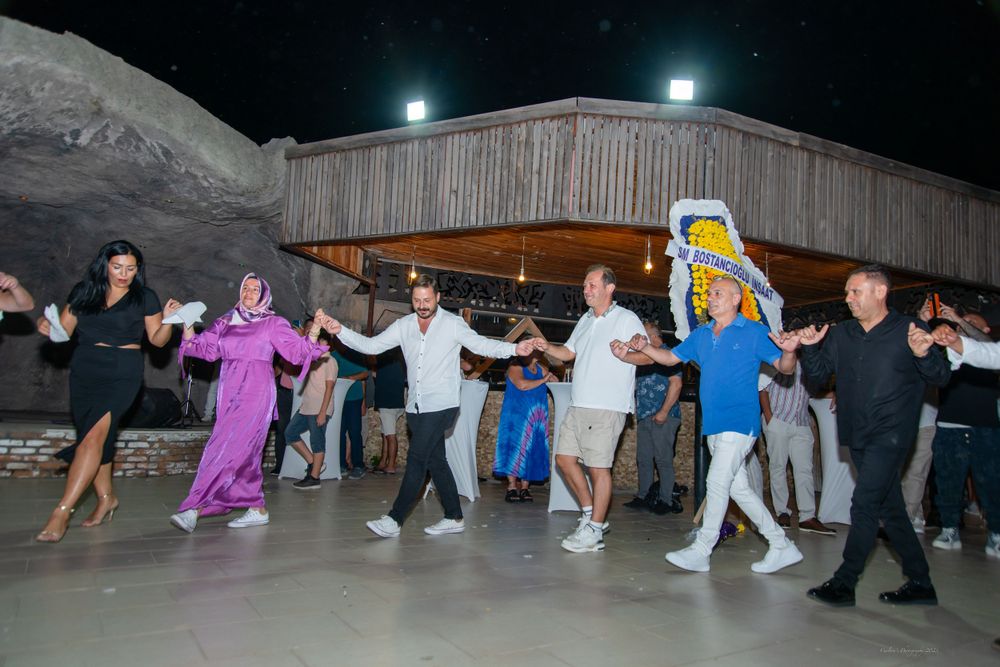 A sequence of dance moves performed on a wooden floor during an evening social gathering with people in coordinated motion.