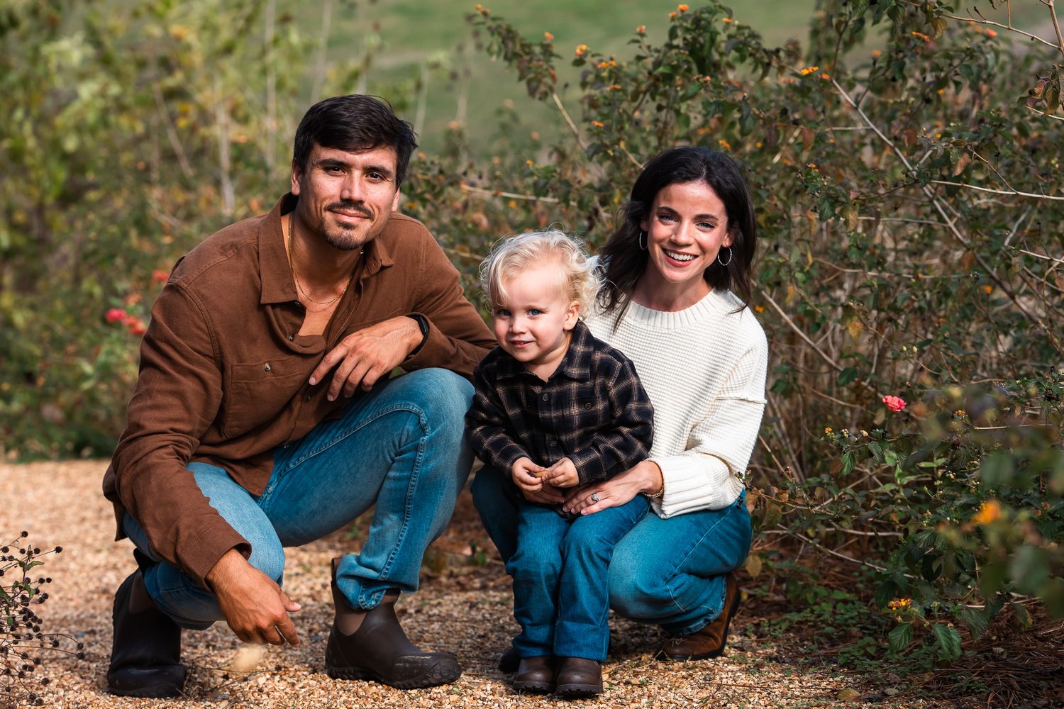 Family poses together in autumn apple orchard during golden hour.