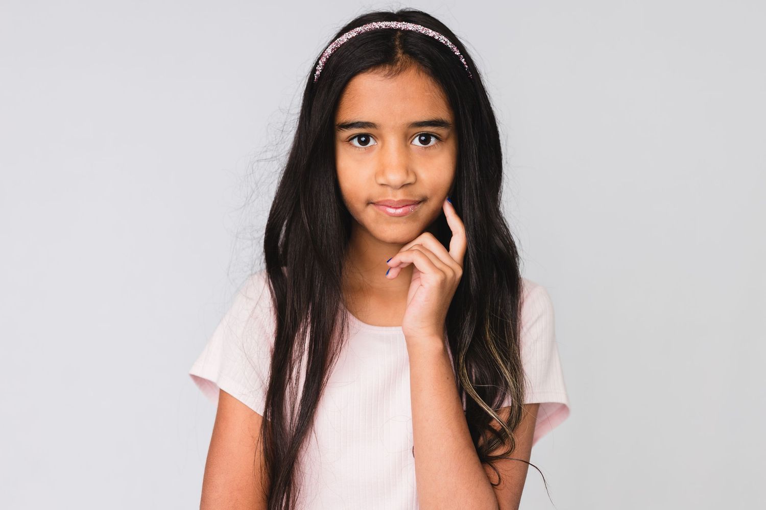 Studio portrait of a child in a burgundy sweater with curly hair and hair clips.