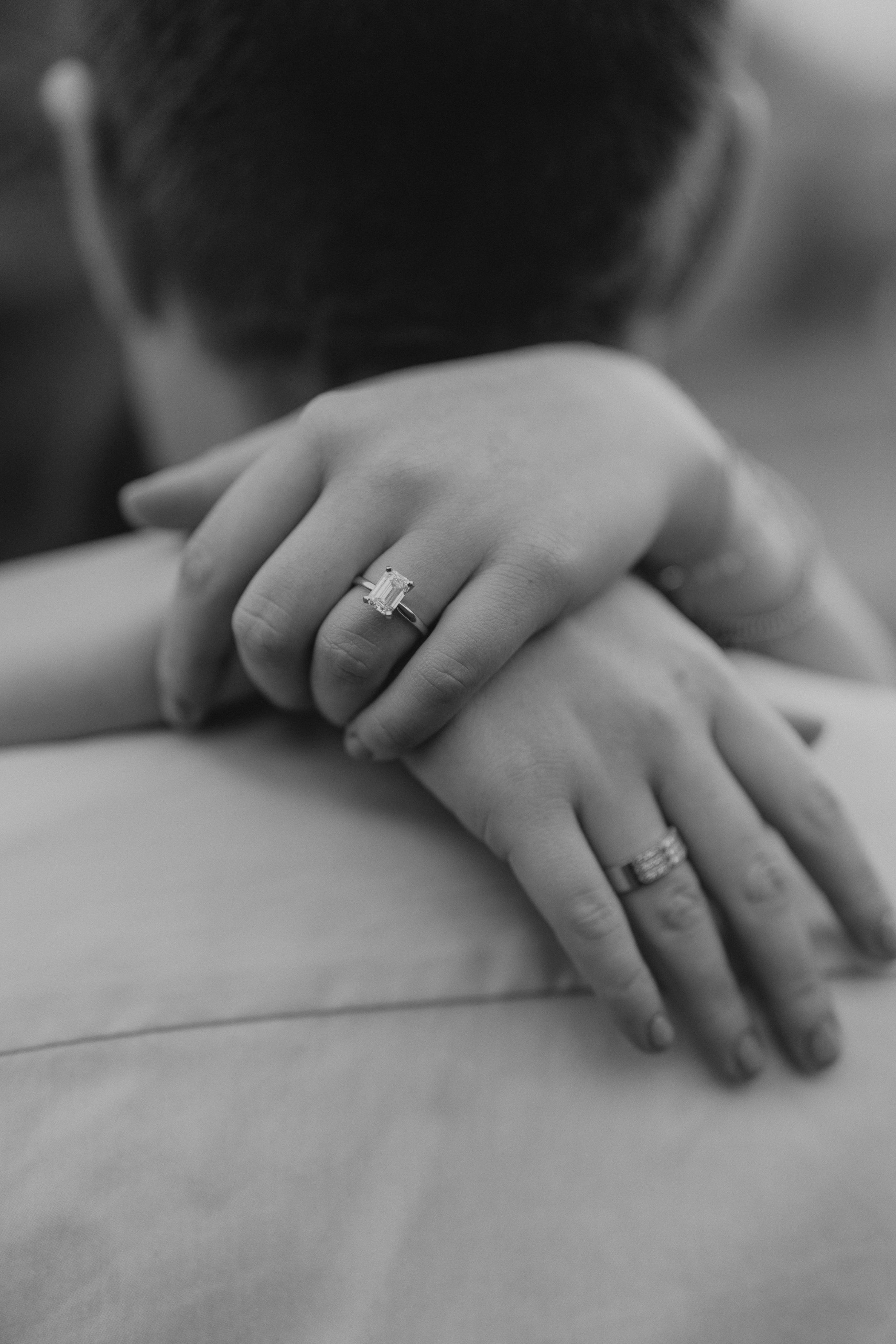Close-up of hands with wedding rings embracing in black and white.