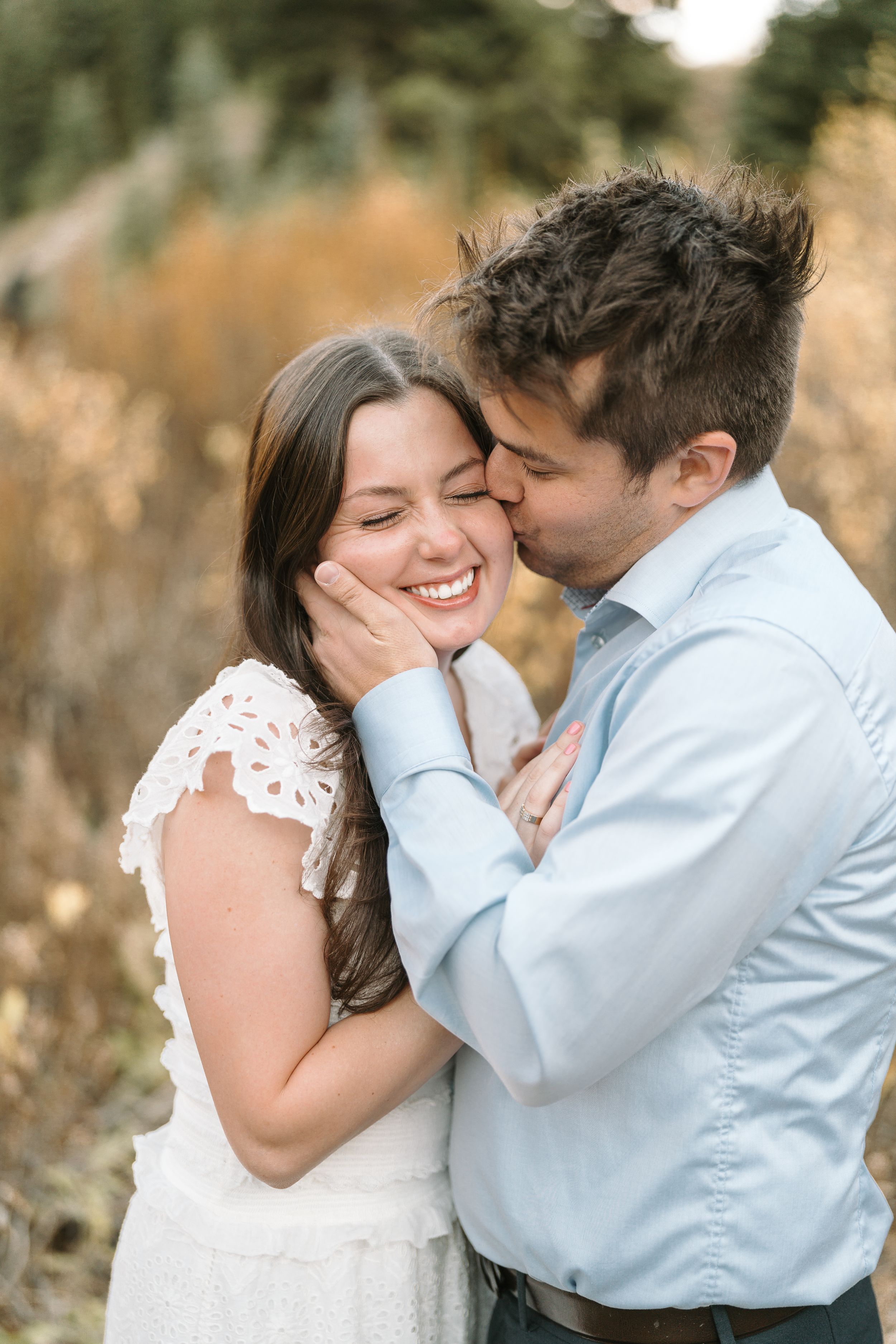 Intimate moment shared between couple in golden mountain meadow.