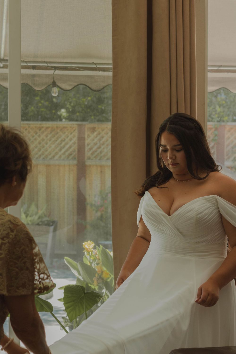 Grandmother fixing bride's dress on wedding day.