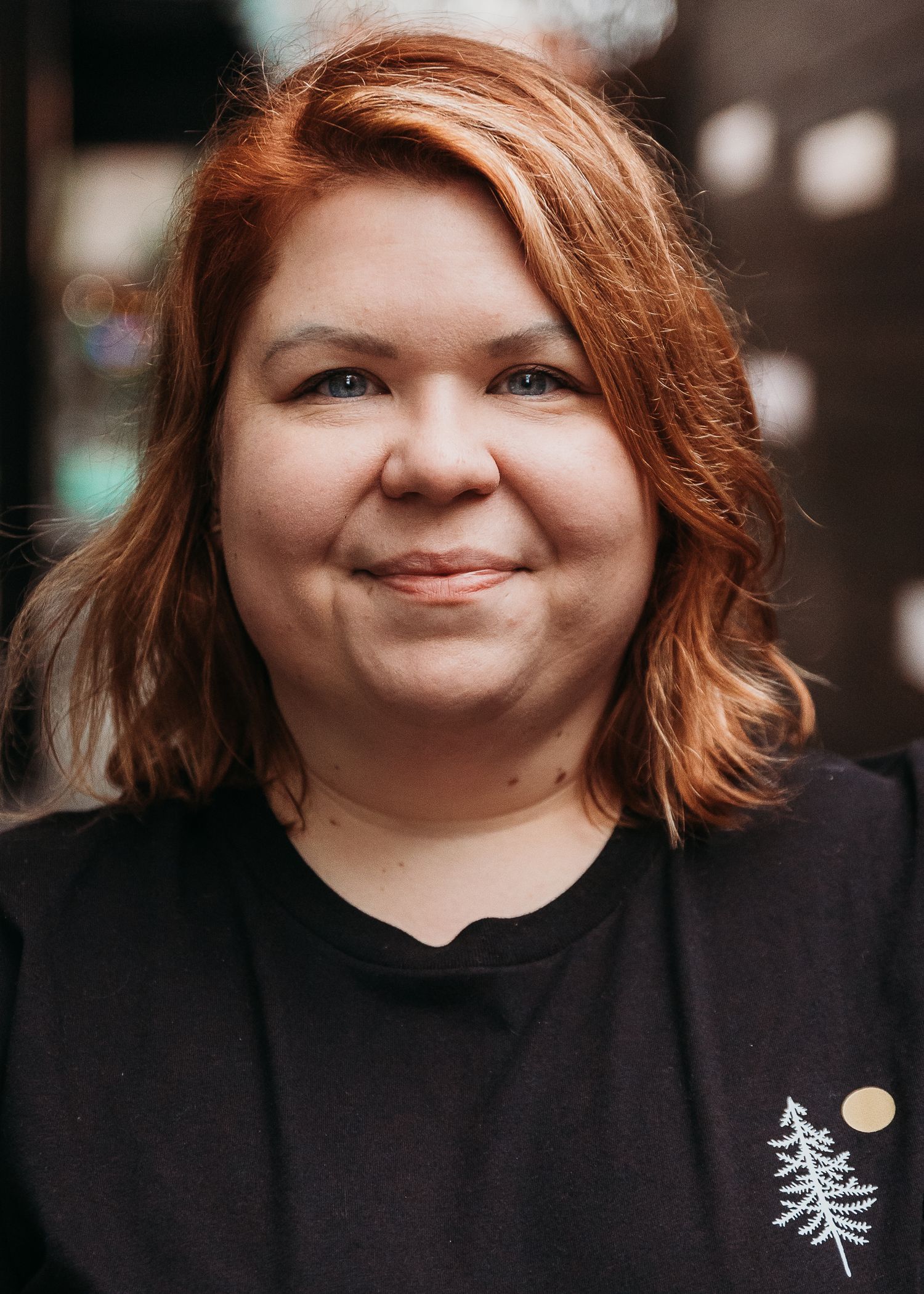 A close up portrait of someone wearing a black t-shirt with a pine tree design.