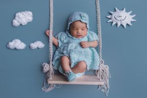 Newborn baby sitting on swing photoshoot in studio