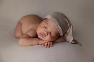 Newborn baby laying tummy down with chin on hands