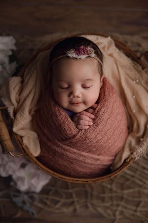 newborn baby wrapped up inside of basket prop closeup of face and hands