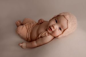 milestone photoshoot of baby laying on back looking at camera